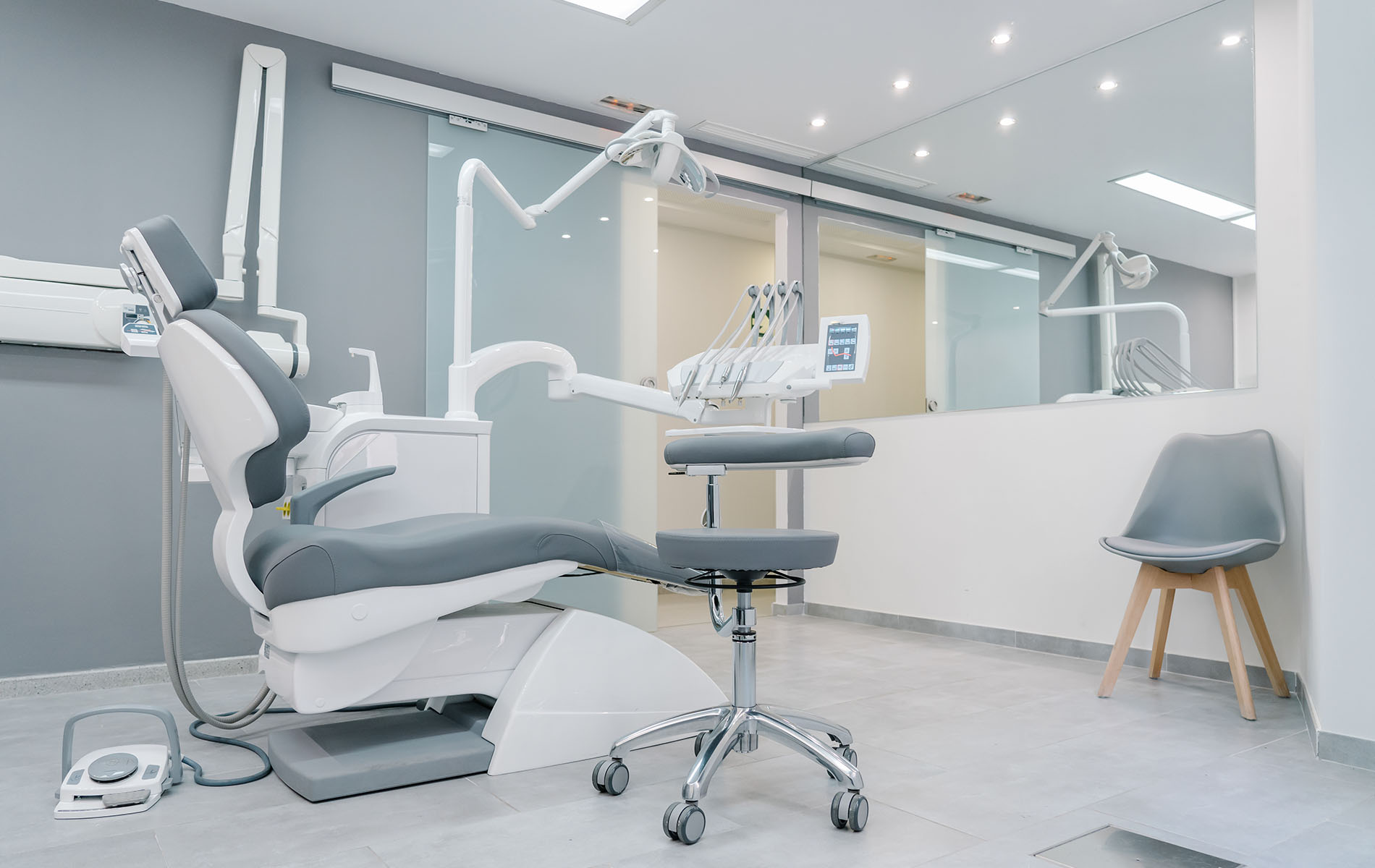 The image shows a modern dental office interior with a chair setup, a dental chair, and equipment typically found in such a setting.